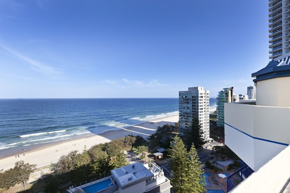 A beach view from a high-rise building with a pool and a view of the ocean.