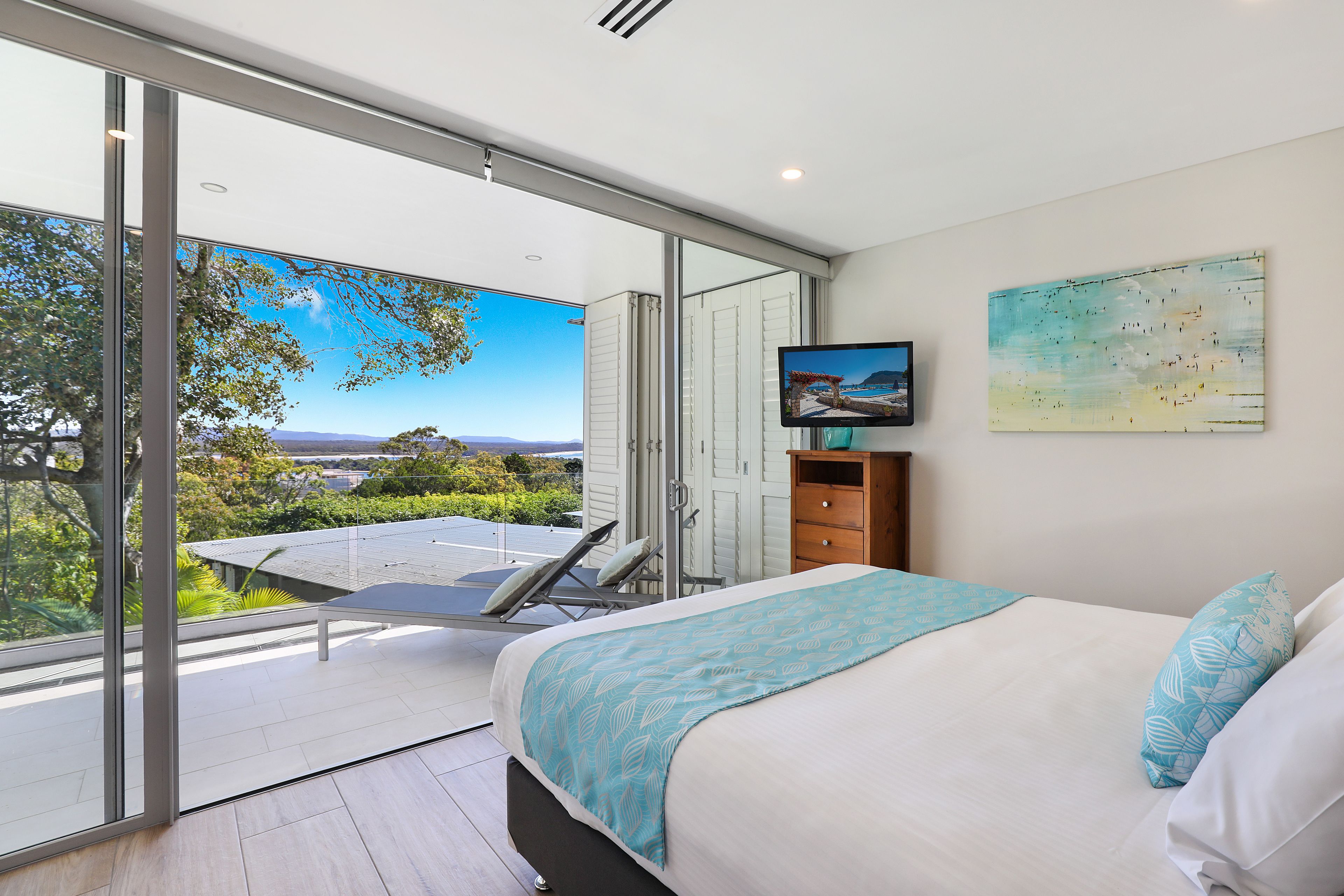 Un dormitorio con una cama grande, televisión y balcón con vistas.