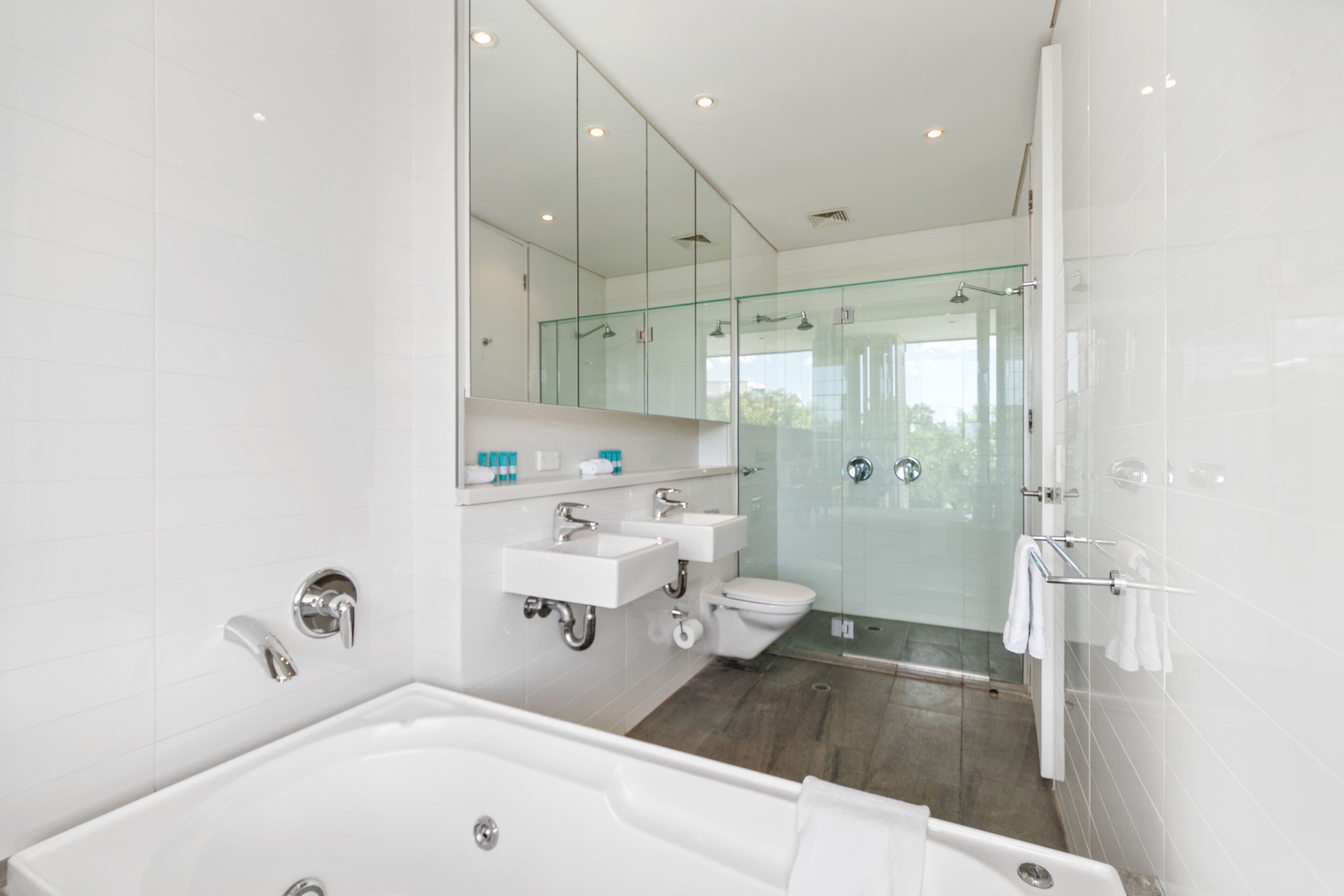 Een moderne badkamer met een glazen douchecabine, een vrijstaand bad en een wastafel met spiegel.