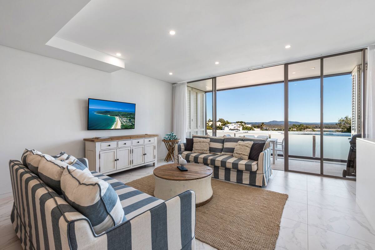 A modern living room with a sofa set, a coffee table, and a TV on the wall.