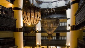 A spacious lobby with a central seating area, high ceilings, and ornate chandeliers.