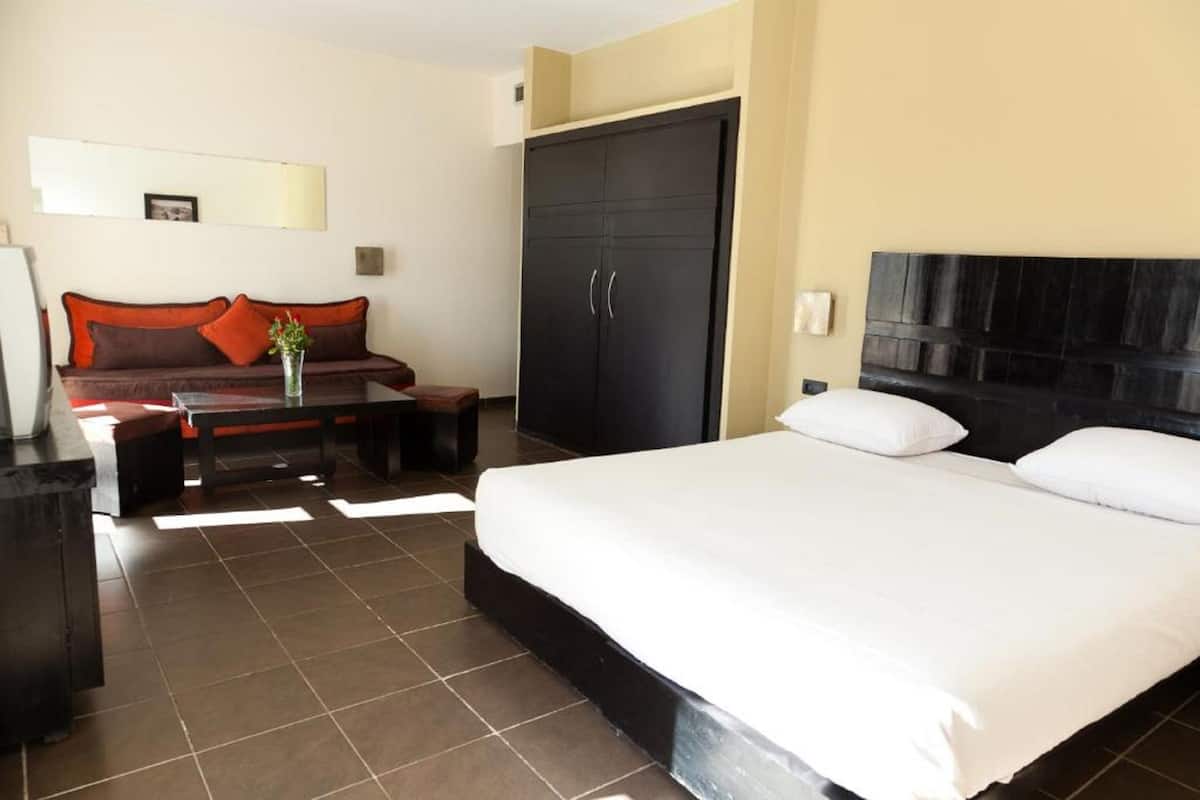 A hotel room with a bed, a sofa, a coffee table, and a wardrobe.