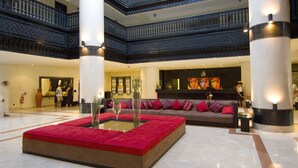 A spacious lobby with a central red seating area, a reception desk, and a staircase. - Royal Decameron Tafoukt Beach Resort & Spa - All Inclusive (Agadir)