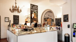 Um café com balcão de vidro, lustre e área de recepção.