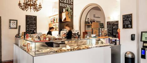 A cafe with a glass counter, a chandelier, and a reception area.