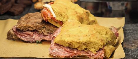 A sandwich with a yellow bread base and red meat, placed on a tray.