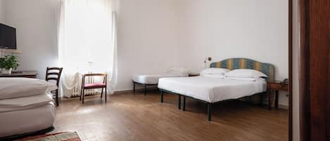 A bedroom with a bed, a chair, a small table, and a nightstand.