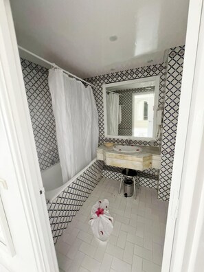 A small bathroom with a shower, a sink, and a mirror.