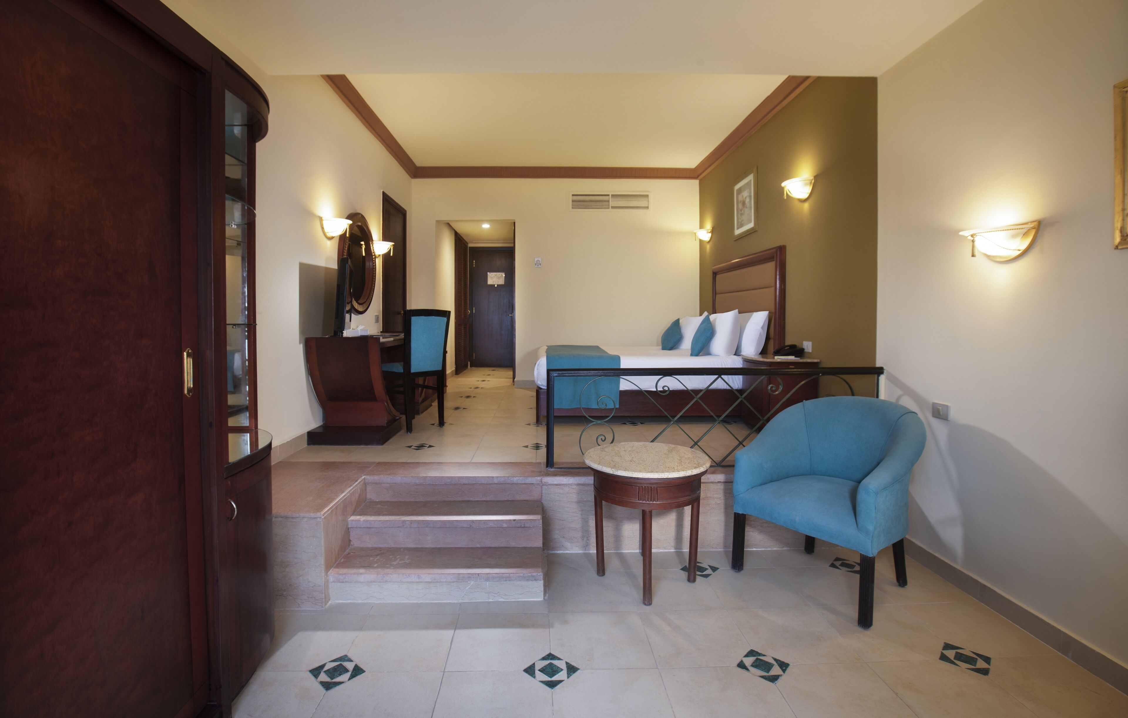 A hotel room with a bed, a chair, a small table, and a staircase leading to another room.
