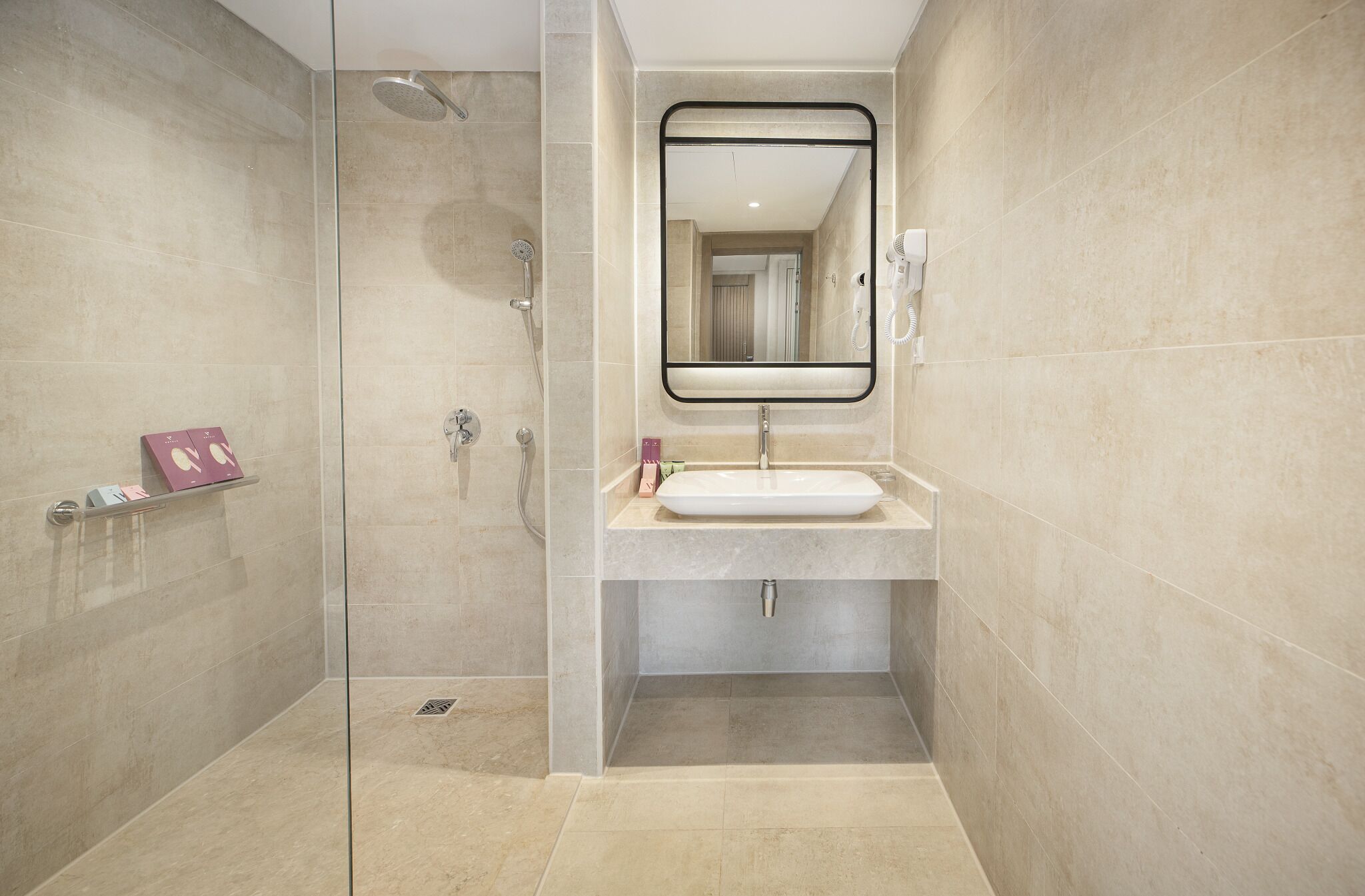 A modern bathroom with a glass-enclosed shower, a white sink, and a large mirror.