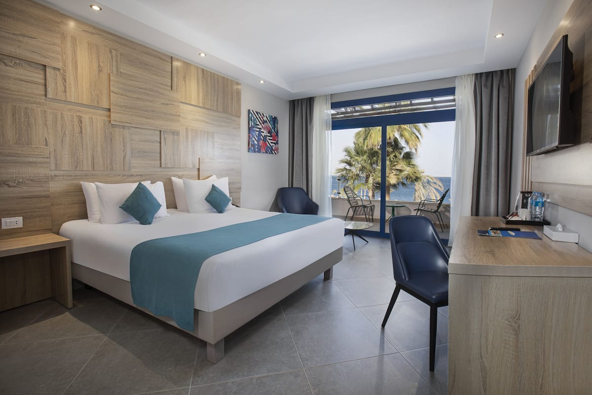 Una habitación de hotel moderna con una cama grande, un escritorio y vistas al océano.