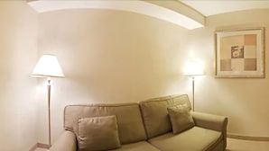 A beige sofa with two pillows, two floor lamps, and a framed picture on the wall. - EconoLodge Downtown Toronto (Toronto)