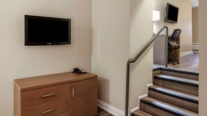 A staircase with a handrail, a wooden cabinet with drawers, and a flat-screen TV mounted on the wall. - EconoLodge Downtown Toronto (Toronto)