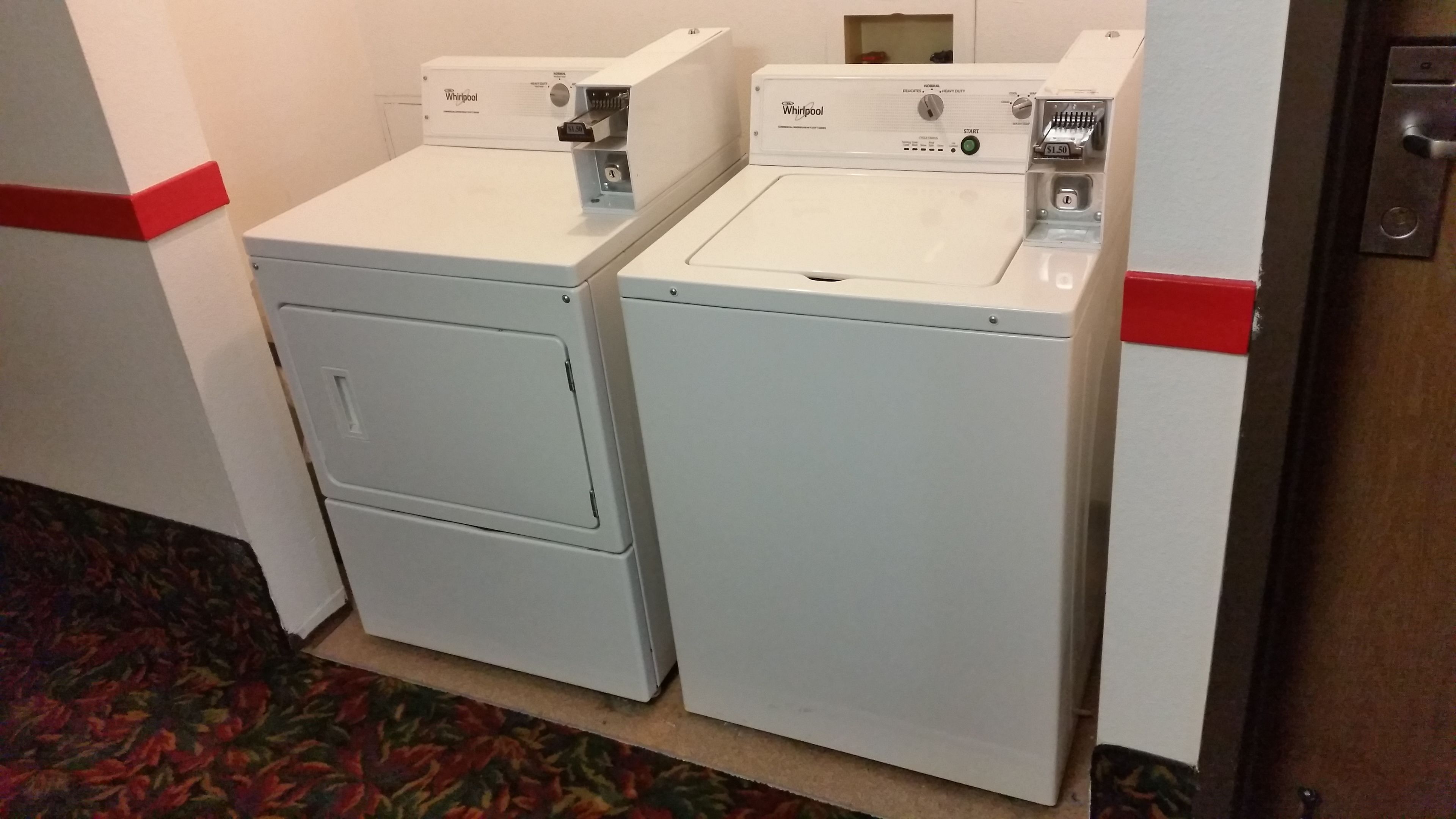 Two Whirlpool front-loading washing machines in a hotel room.