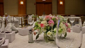 Una mesa de banquete dispuesta con manteles blancos, centros de mesa florales y copas de vino.