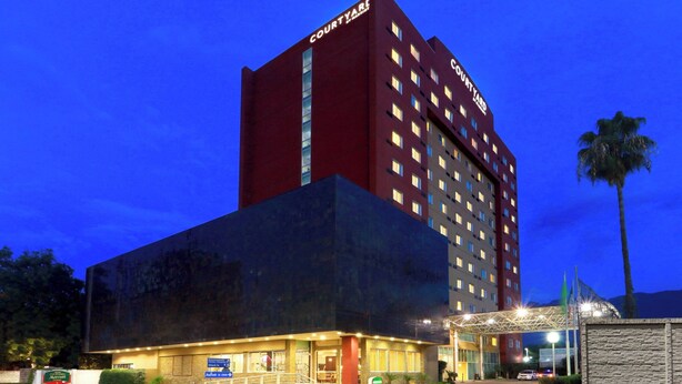 Hotel Courtyard con diseño moderno, que presenta una entrada destacada con un paseo techado y un estacionamiento.