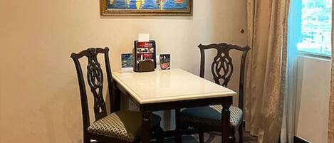 Un comedor con una mesa y cuatro sillas, un cuadro en la pared y una ventana con cortinas.