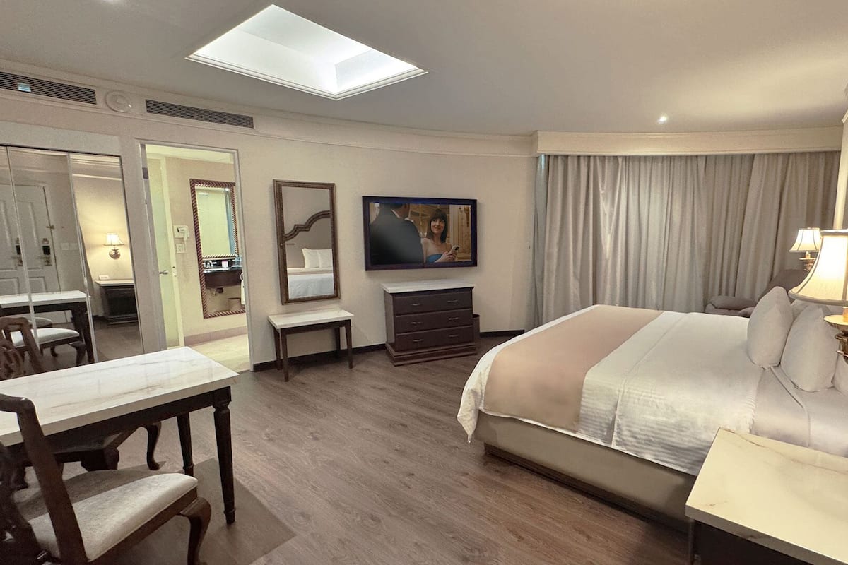 Habitación de hotel con cama, escritorio, silla, televisor y ventana grande.