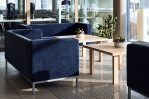 Un área de estar moderna con asientos, una mesa de centro y una planta en maceta.