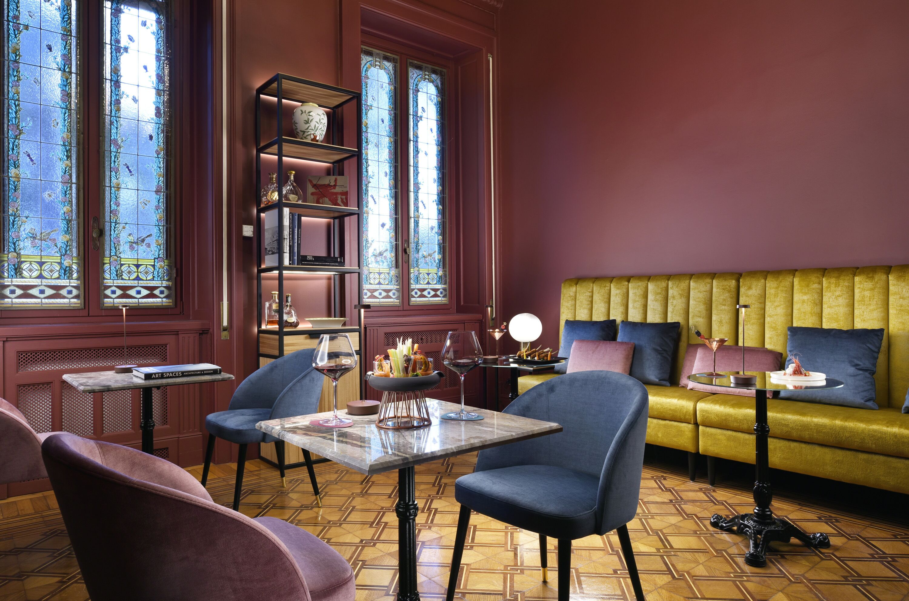 Een kamer met een bank, stoelen, een tafel en een boekenkast.