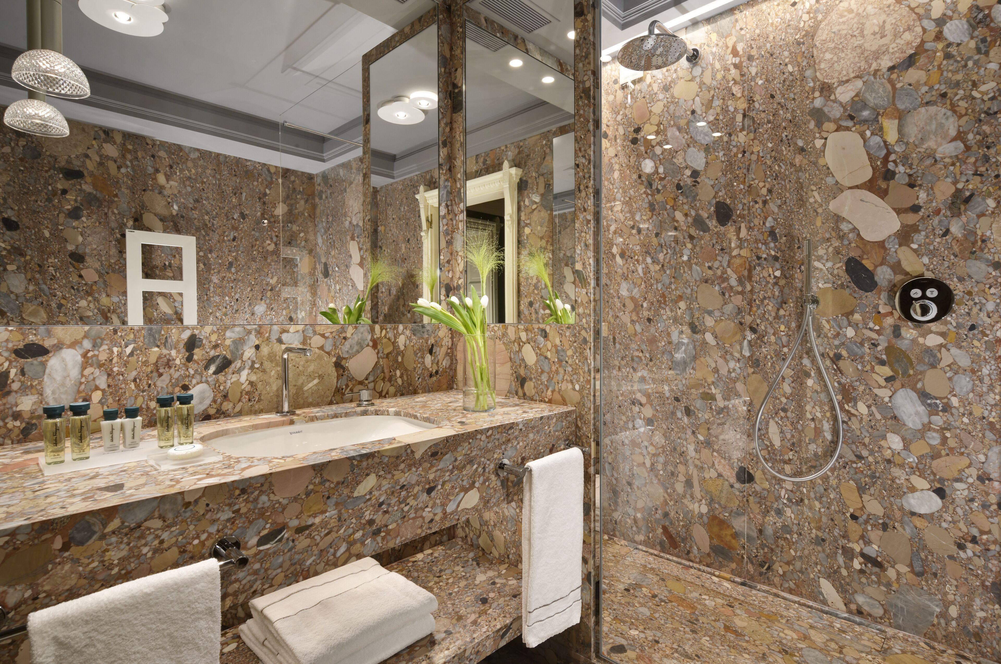 A bathroom with a granite countertop, a sink, a mirror, and a shower.