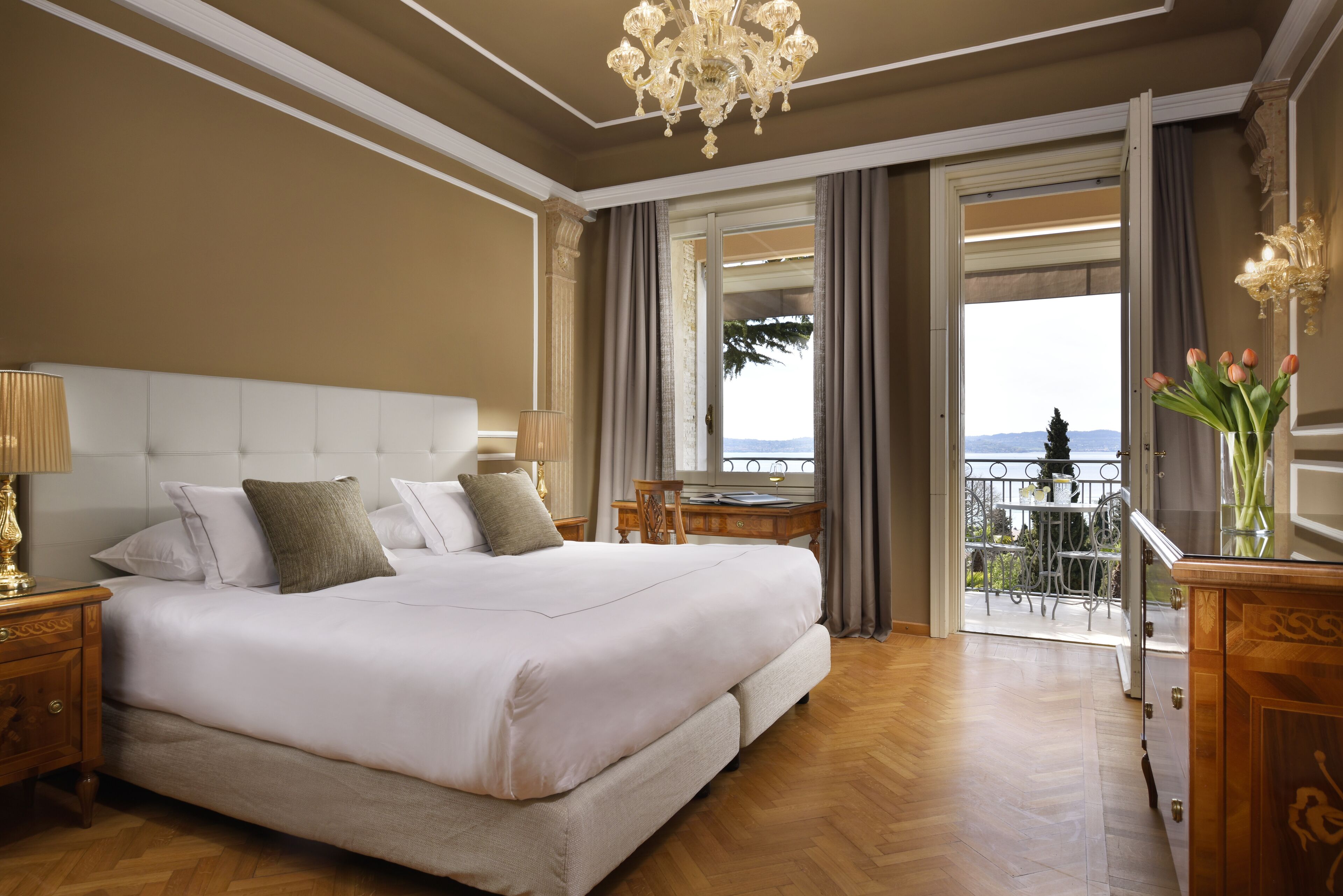 Ein geräumiges Schlafzimmer mit einem großen Bett, einem Holznachttisch, einem Schreibtisch und Blick ins Freie.