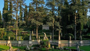 Un jardin à la française agrémenté de statues, d’une fontaine et d’une balustrade en pierre.