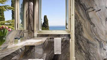 Un bagno con una grande finestra, pareti in marmo, una vasca e un lavandino.