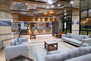 A lobby with a reception desk, sofas, and a coffee table. - Gaddis Hotel (Luxor)