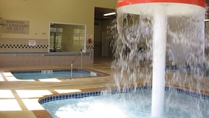 An indoor pool area with a water feature, a lifeguard warning sign, and a 911 emergency phone. - Country Inn & Suites by Radisson, Houghton, MI (Houghton)