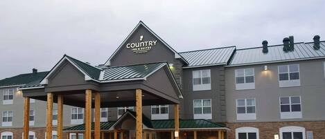 A Country Inn & Suites by Radisson building with a covered entrance, multiple windows, and a parking lot.