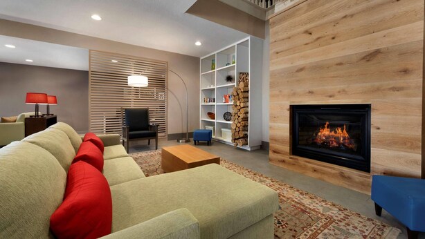 A modern living room with a sofa, a fireplace, and a wooden wall. - Country Inn & Suites by Radisson, Houghton, MI (Houghton)