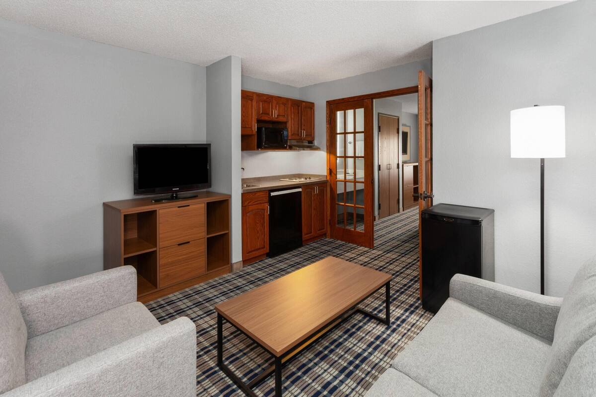 Un espacio habitable pequeño con televisión, kitchenette y zona de estar.