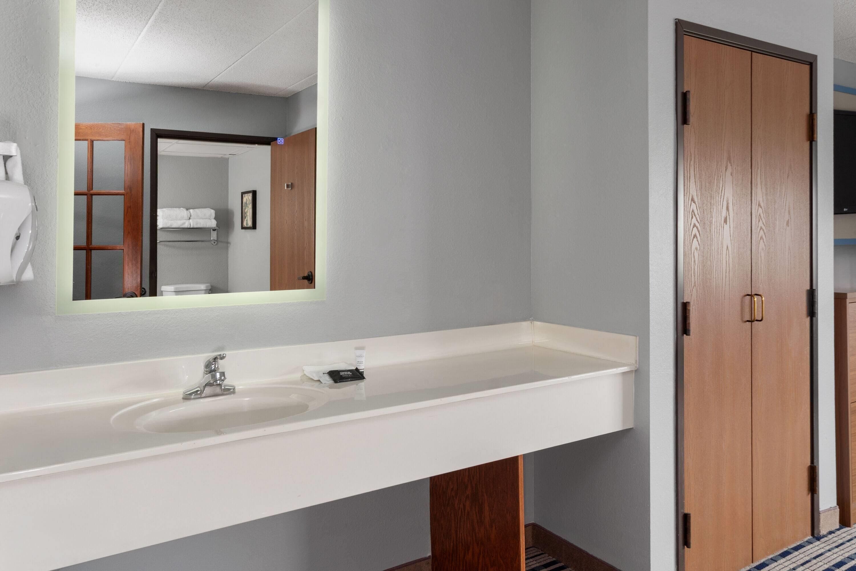 Une salle de bain avec un lavabo blanc, un miroir et des portes en bois.