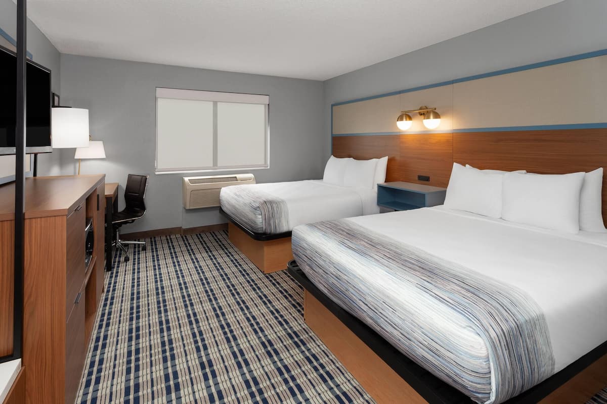Habitación de hotel con cama, mesitas de noche, escritorio, silla, televisión y ventana.
