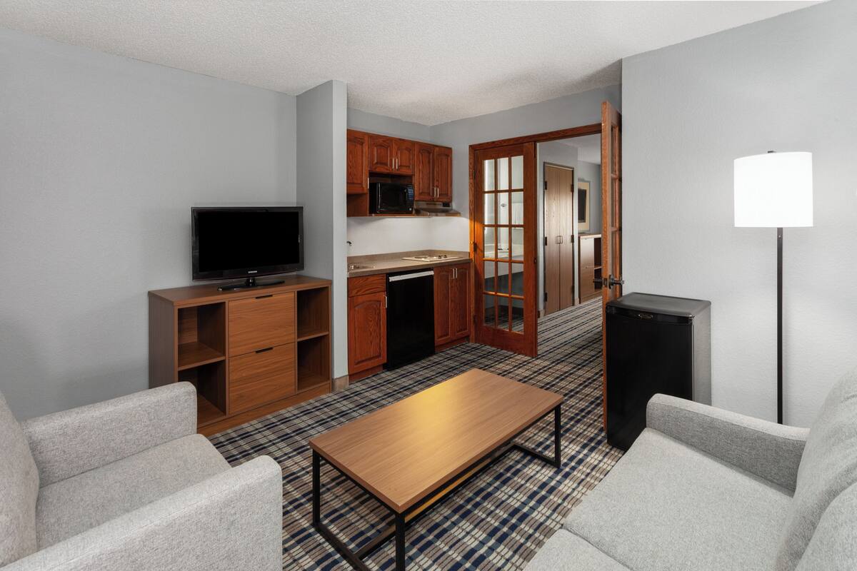 Un espacio habitable compacto con televisor, kitchenette y zona de estar.
