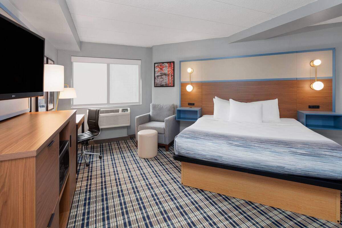 Habitación de hotel con cama, escritorio, silla, televisor y obras de arte.