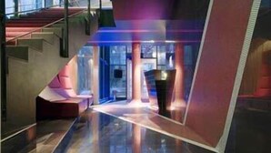 A modern interior with a reflective floor, a staircase, and a seating area.