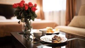 A dining table with a dessert plate, a vase with red roses, and a cup.