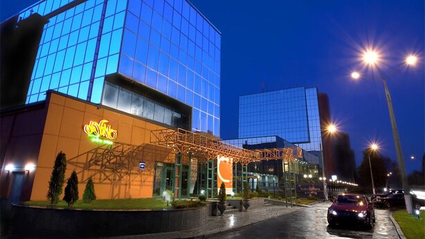 A modern building with a glass facade and a neon sign.