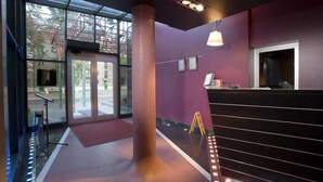 A modern lobby with a large glass entrance, a central pillar, and a reception desk.