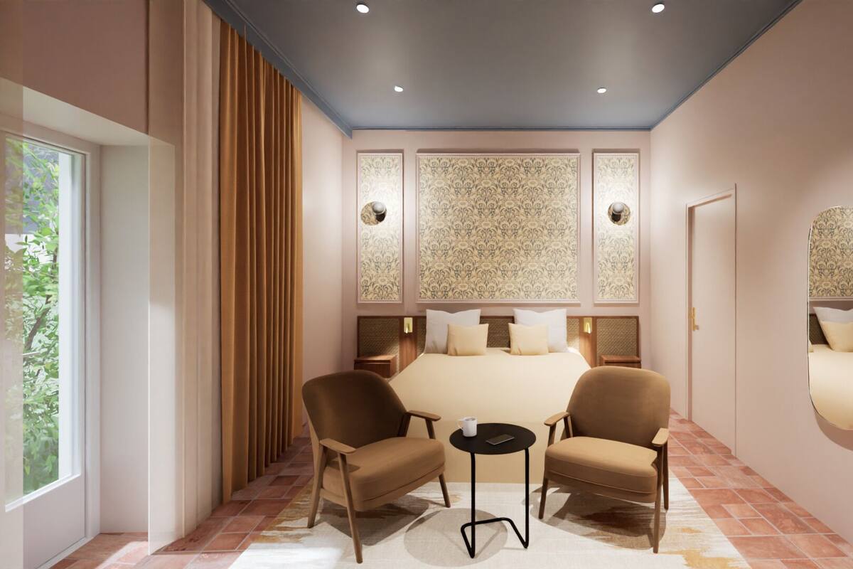 Habitación de hotel con una cama grande, dos sillones, una mesita y un espejo en la pared.