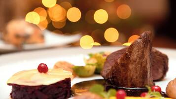 A dessert plate with various items including a piece of meat, a slice of cake, and some garnishes.