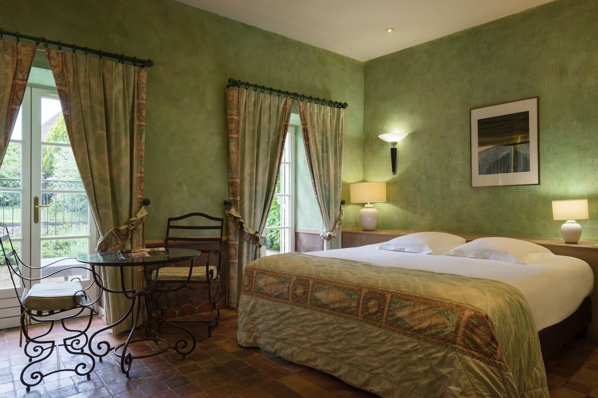 Una habitación con cama, mesa, silla y cortinas.