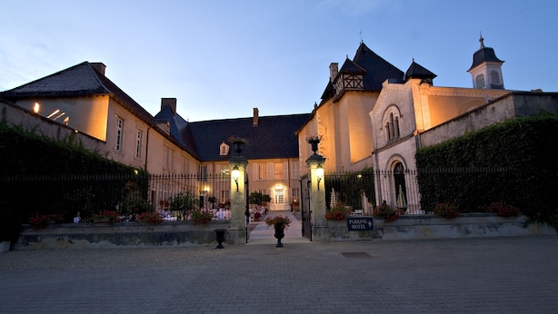 A historic building with a central courtyard, a bell tower, and a sign indicating a hotel.
