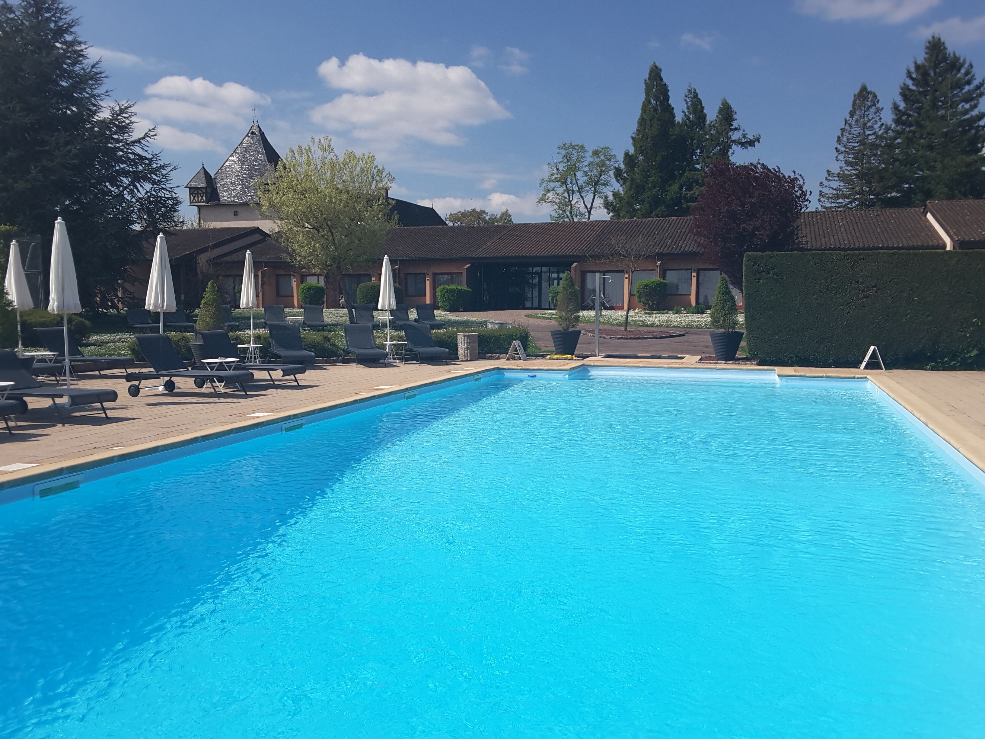A swimming pool with lounge chairs and umbrellas, surrounded by buildings with a traditional architectural style.