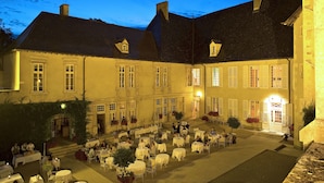 A courtyard with outdoor seating, a building with multiple windows, and a well-lit entrance.