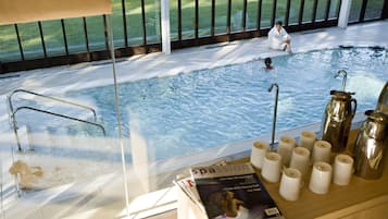 Un espace piscine délimité par une paroi en verre, un magazine et plusieurs tasses à café posées sur un comptoir.