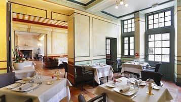 A restaurant with multiple tables set for dining, large windows, and a fireplace in the background.