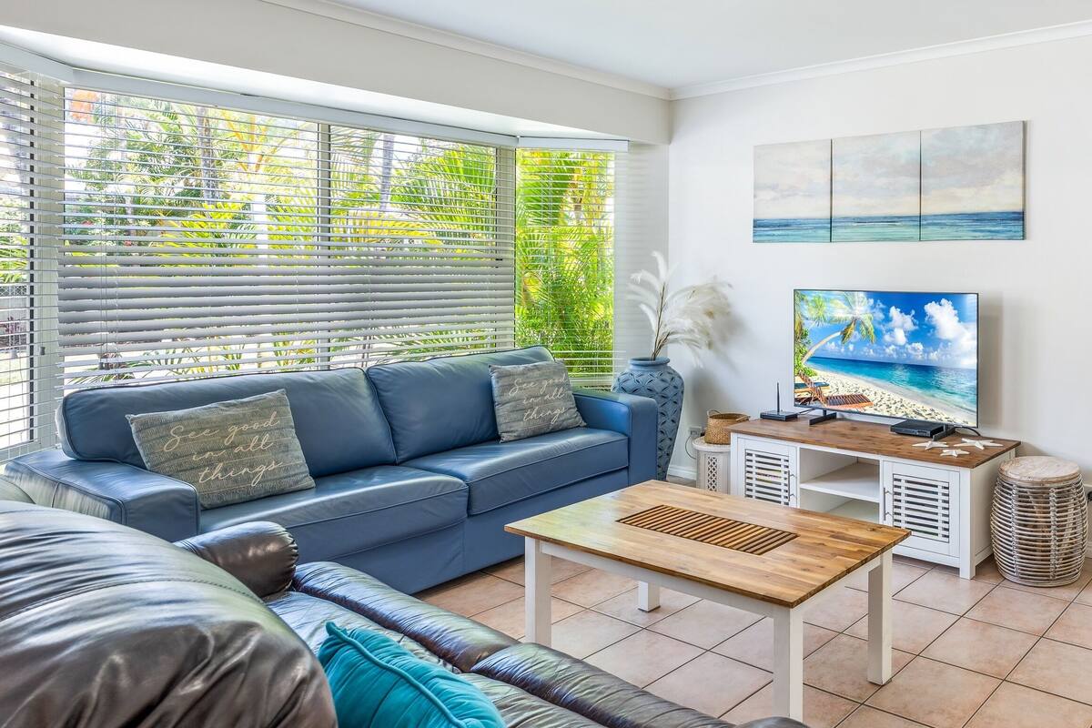 A modern living room with a blue sofa, a wooden coffee table, and a television.
